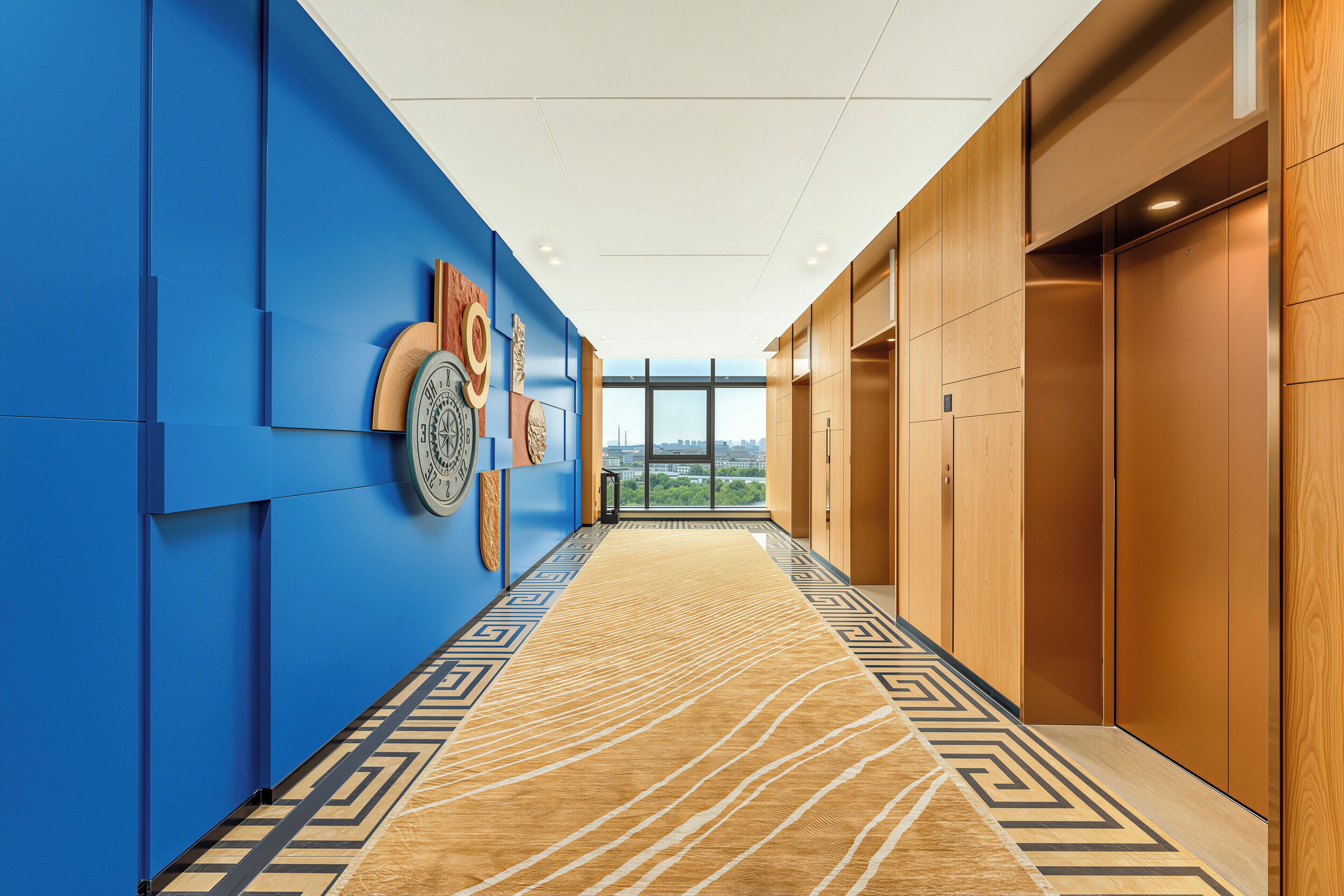 Un pasillo con paredes azules, puertas de madera y una alfombra estampada.