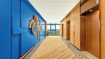Un pasillo con paredes azules, puertas de madera y una alfombra estampada.