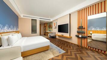 A modern hotel room with a large bed, a desk, a flat-screen TV, and a mirror.