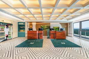 A modern reception area with a reception desk, a vending machine, and a view of the outdoors.