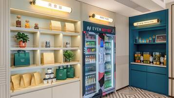 Un hall d’hôtel équipé d’un distributeur automatique de boissons, d’un point d’hydratation et d’un présentoir de sacs de courses à l’effigie de la marque.