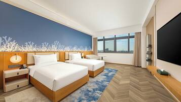 A hotel room with two beds, a large window, a flat-screen TV, and a city view.