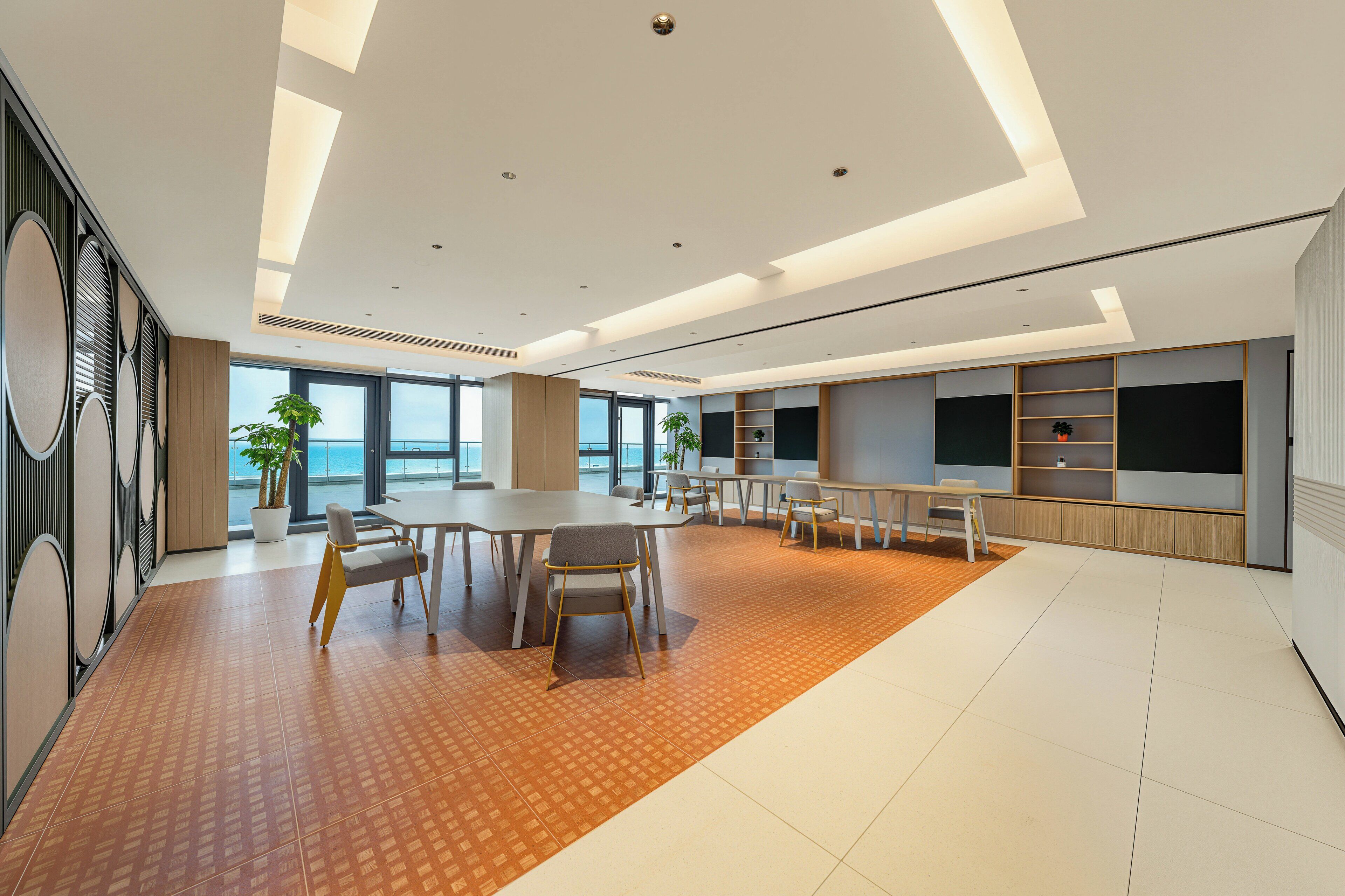 A spacious conference room with a large table, chairs, and a television screen.