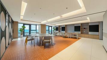 A spacious conference room with a large table, chairs, and a television screen.