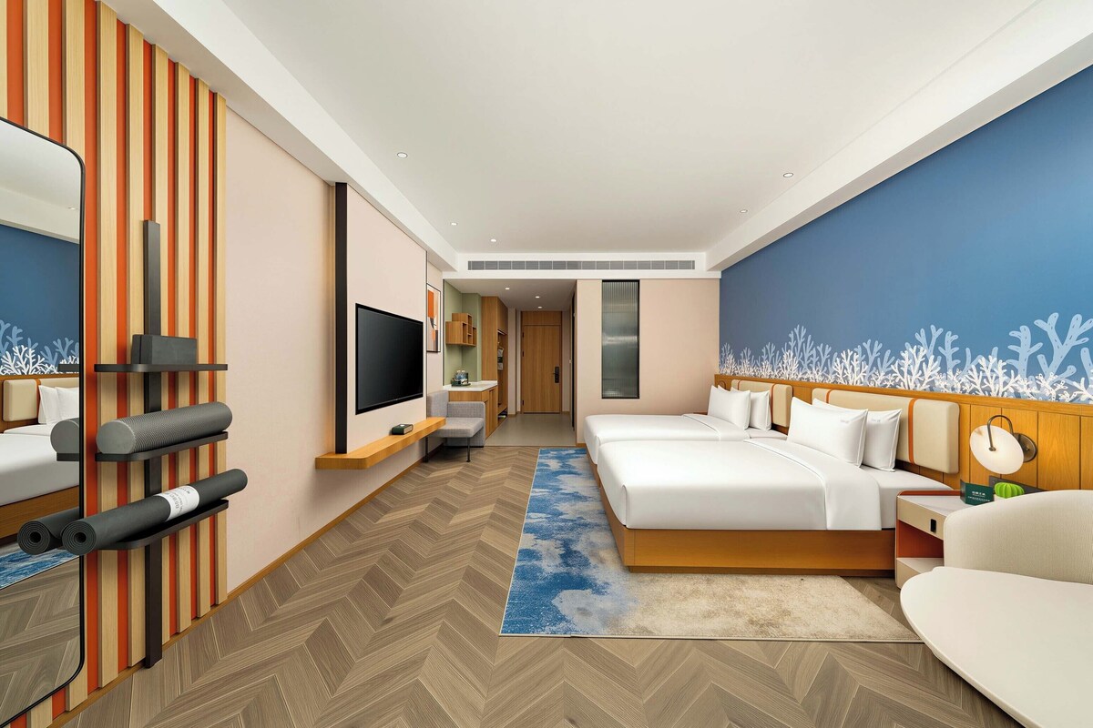 Et moderne hotelværelse med en stor seng, et fjernsyn, et skrivebord og et siddeområde.