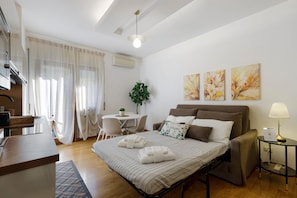 A hotel room with a bed, bedside table, lamp, air conditioning unit, and a dining area with a table and chairs. - Apartment 'Your Place in Italy - Rome Apt 1' with Wi-Fi and Air Conditioning (Roma)