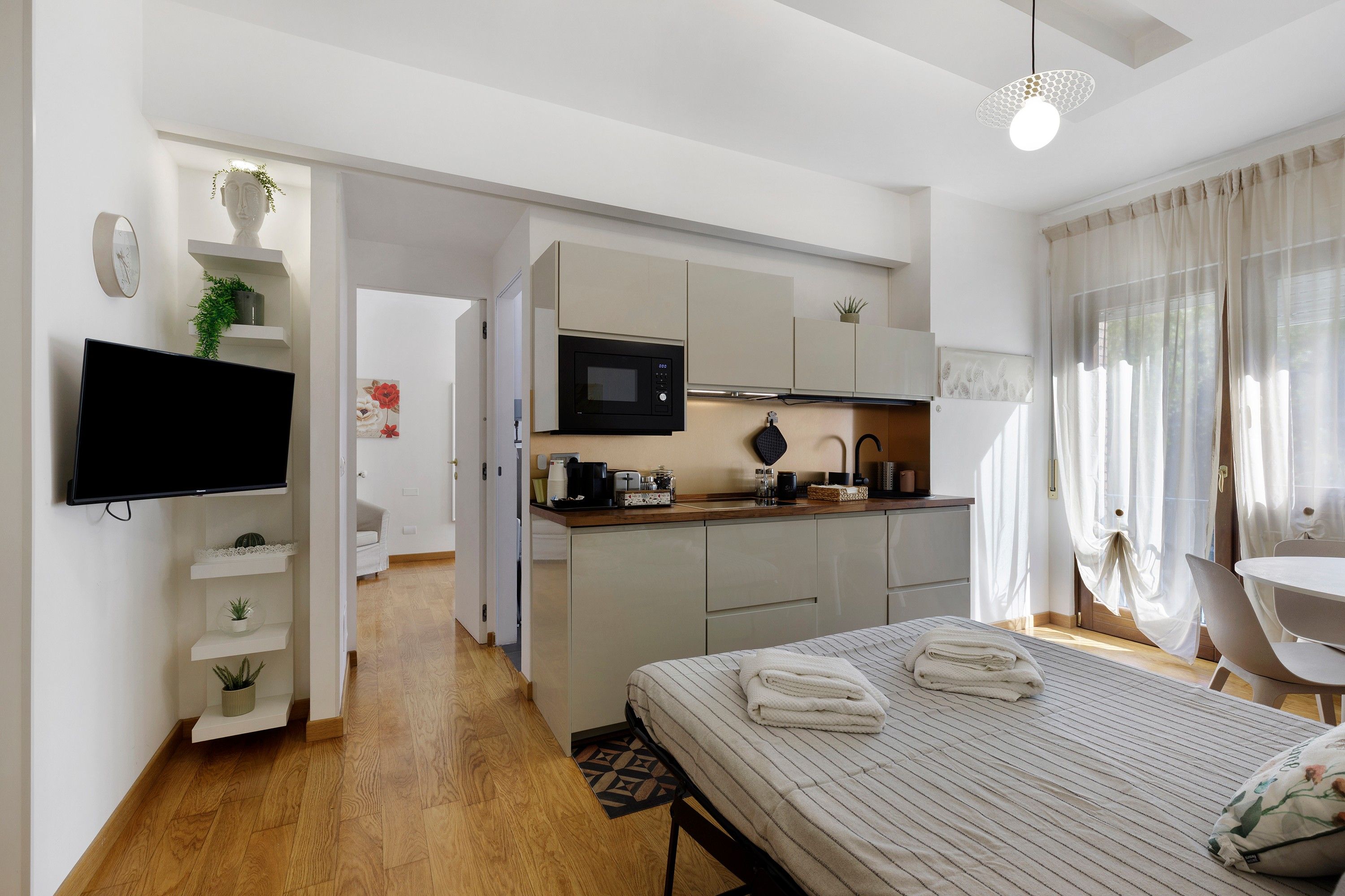 Une chambre d’hôtel moderne équipée d’un lit, d’un téléviseur à écran plat, d’une kitchenette et d’un coin repas.