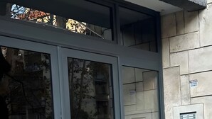 Entrada de un edificio con puerta de vidrio, marco de metal y pared de piedra.