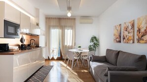 Una cocina moderna con armarios blancos, un microondas y un comedor con una mesa y sillas.