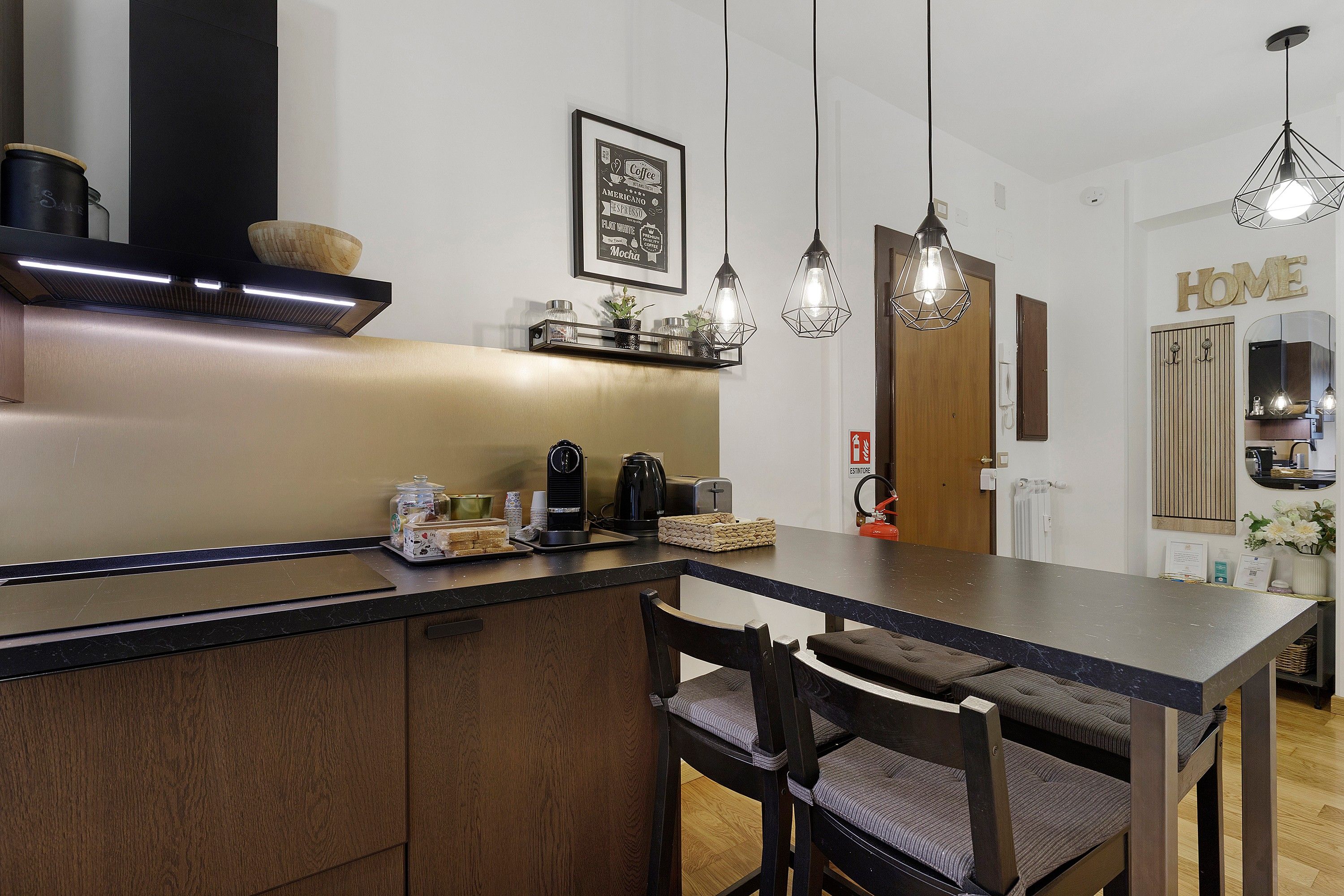 Una cucina moderna con isola centrale, illuminazione a sospensione e pensili in legno.