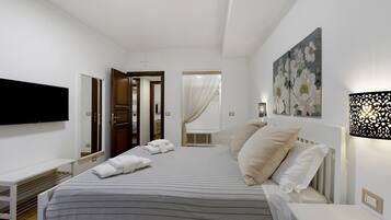 Un dormitorio moderno con una cama, mesitas de noche, un televisor de pantalla plana y un cuadro en la pared.