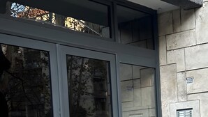 L'ingresso di un edificio con una porta in vetro, un muro in pietra e un sistema di ventilazione.
