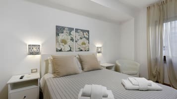 Una camera d'albergo con un letto, due comodini, una sedia e un quadro appeso al muro.