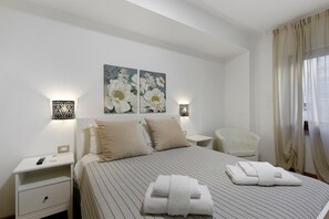 A hotel room with a bed, two nightstands, a chair, and a painting on the wall. - Apartment 'Your Place in Italy - Rome Apt 2' with Balcony, Wi-Fi and Air Conditioning (Roma)