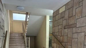 Una scala con corrimano che porta a un pianerottolo con una porta in vetro.