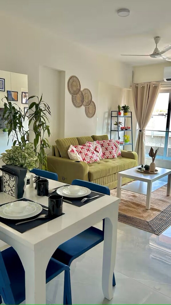 A modern living room with a dining area, a ceiling fan, and a view of the outdoors.