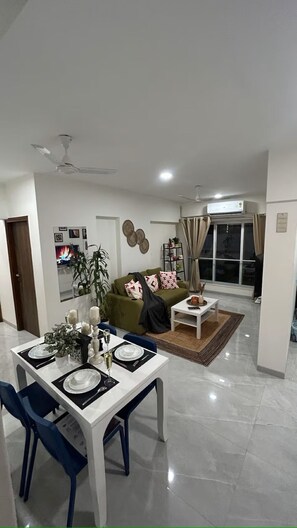 A modern living room with a dining area, a sofa, a coffee table, and a TV.