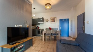 A living room with a TV, sofa, and dining area. - La Parenthèse d'Uzès - Avec Parking Privé (Uzes)