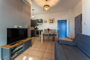 Ein Wohnzimmer mit Fernseher, Sofa und Essbereich.