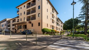 A multi-story building with balconies, a crosswalk, and a street lamp. - La Parenthèse d'Uzès - Avec Parking Privé (Uzes)