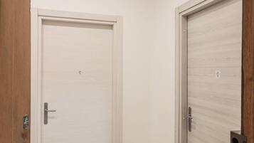 Deux portes fermées, avec un revêtement en bois clair, une poignée en métal et une petite étiquette sur la porte de droite.