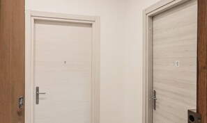 Deux portes fermées, avec un revêtement en bois clair, une poignée en métal et une petite étiquette sur la porte de droite.