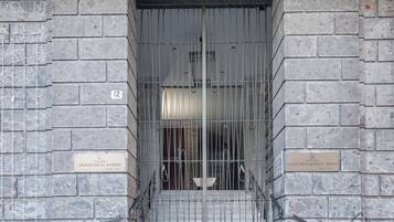 Une entrée fermée par un portail, agrémentée de deux plaques commémoratives, l’une dédiée à Domenico Parisi et l’autre à Luigi Francesco Rissio, ainsi que le chiffre « 12 » peint sur le mur.