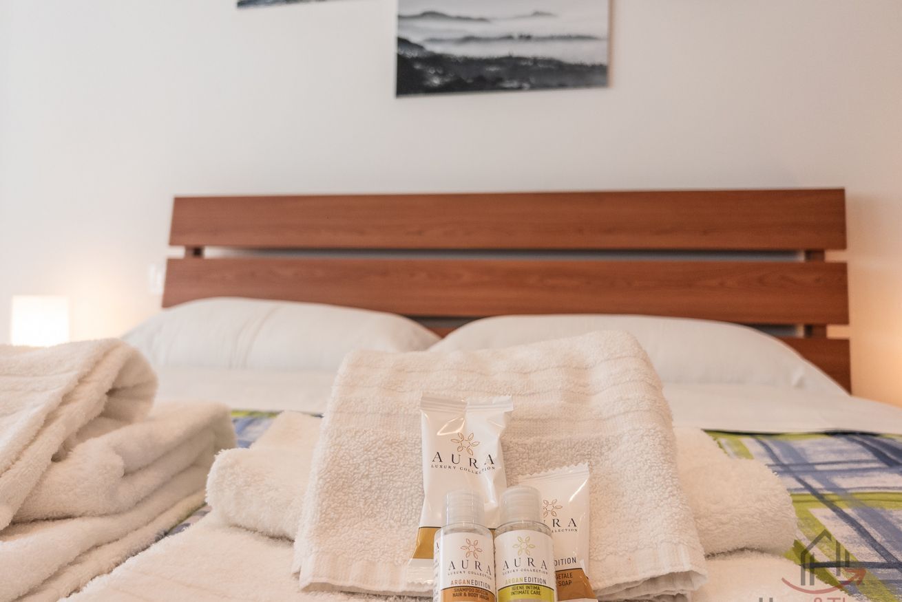 Una cama bien hecha con toallas dobladas y botellas de loción.