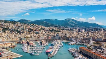 Un paysage urbain côtier avec un port de plaisance, des bâtiments et des montagnes en arrière-plan.
