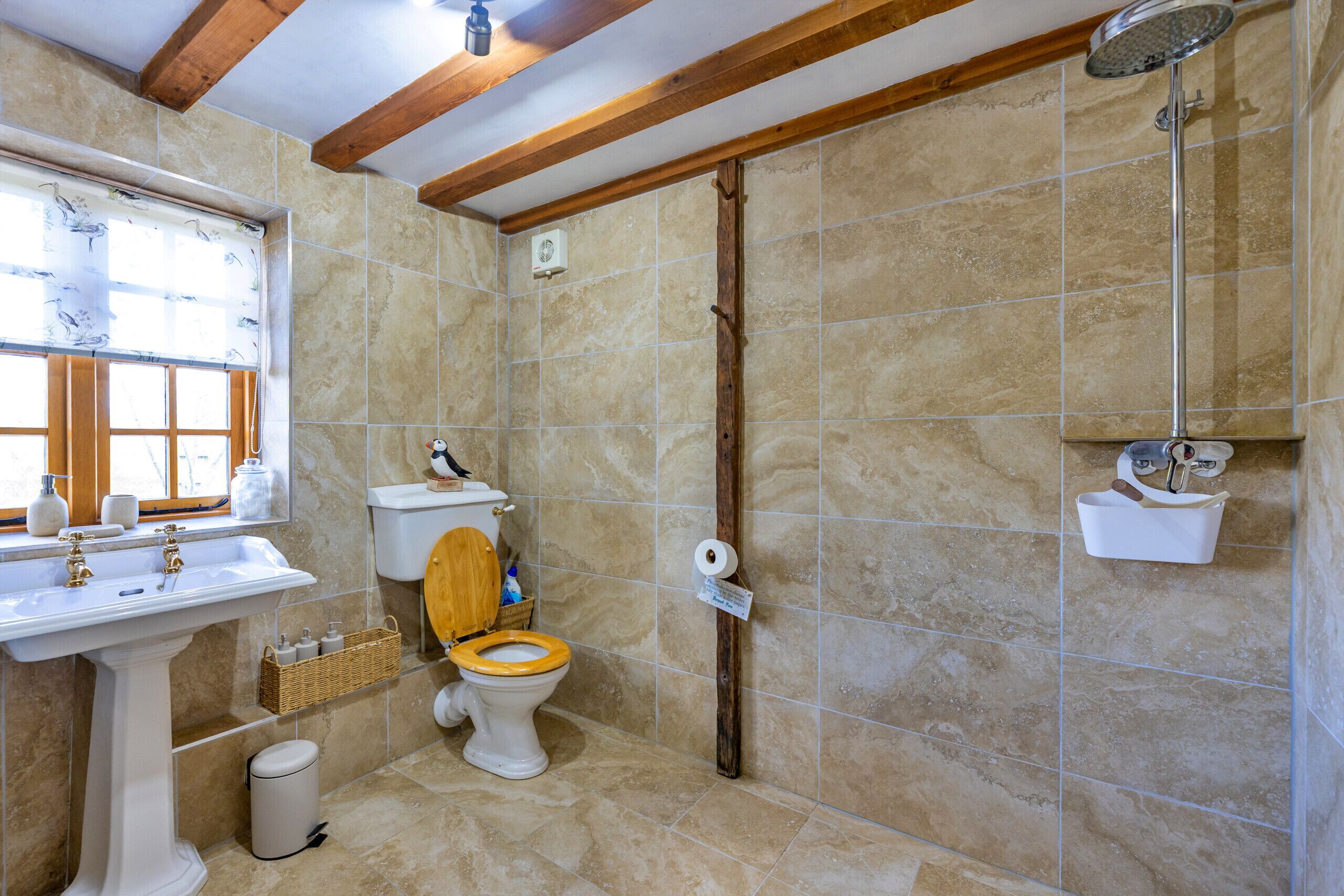 Et badeværelse med et konsolbordvask, toilet, brusebad og et vindue med udsigt.
