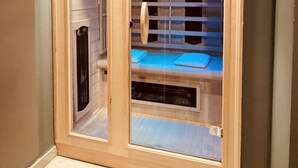 Uma sauna com estrutura de madeira, portas de vidro e um banco interno.