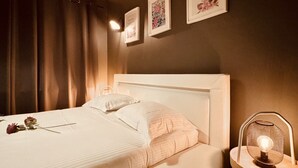 Uma cama bem arrumada com lençóis brancos, um abajur e arte floral emoldurada na parede.
