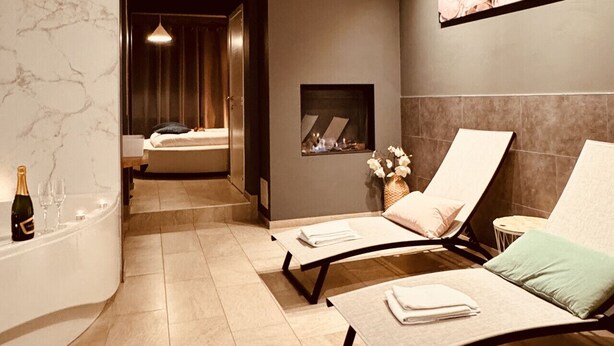 Um spa moderno com parede de mármore, lareira e duas poltronas confortáveis.