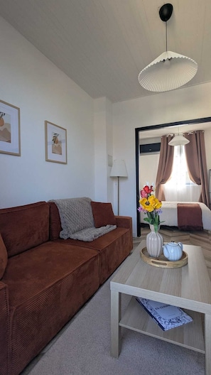 Ein Wohnzimmer mit einer braunen Couch, einem Couchtisch mit Blumenvase und einer Lampe.