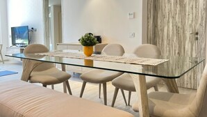 A modern dining area with a glass table, beige chairs, and a potted plant. - Fouka North Coast SA-9B-G02 (Marsa Matrouh)