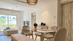 A modern dining area with a glass table, cushioned chairs, and a bench. - Fouka North Coast SA-9B-G02 (Marsa Matrouh)