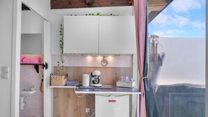 A compact kitchenette with a coffee maker, a small refrigerator, and a sink.