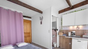 A bedroom with a bed, a bathroom, and a kitchenette.