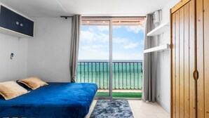 Ein Schlafzimmer mit Bett, Meerblick und einer Schiebeglastür.