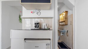 Eine kleine Küche mit Kaffeemaschine, kleinem Kühlschrank und Mikrowelle.