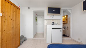 Ein gemütlicher Raum mit Holzschrank, einer kleinen Küchenzeile, einem Bett und einem Badezimmer.