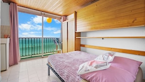 A bedroom with a bed, a view of the sea, and a balcony.