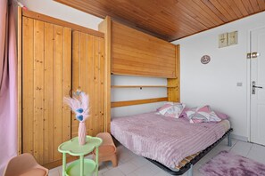 Ein Schlafzimmer mit einem Bett, einem Holzschrank, einem kleinen Tisch und einem Stuhl.