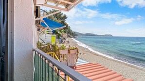 Varanda com vista para uma praia, com visão clara do mar e colinas ao longe.