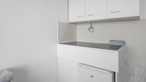 Una cocina con armarios blancos, encimera de acero inoxidable y refrigerador.