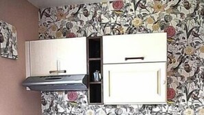 A compact kitchen with white cabinets, a black countertop, and a floral-patterned backsplash. - Charming apartment with swimming pool 6 km from the Vendée beaches (Notre-Dame-de-Riez)