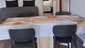 A room with a bed, a table with chairs, a painting on the wall, and a door leading to another room. - Charming apartment with swimming pool 6 km from the Vendée beaches (Notre-Dame-de-Riez)