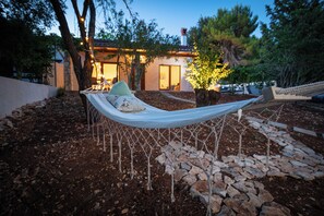 A hammock between trees in a landscaped garden with a building in the background. - Al Pino Blue house by Istra Vacation (Premantura)