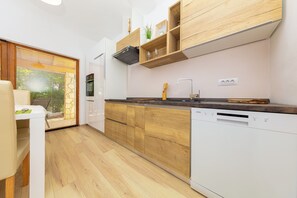 A modern kitchen with wooden cabinets, a dishwasher, and a window with blinds. - Al Pino Blue house by Istra Vacation (Premantura)