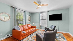 A living room with a sofa, chairs, a television, and a ceiling fan. - Centrally Located in Brownes Addition (Spokane)